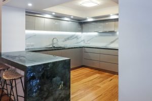A modern kitchen installed on the Gold Coast by Cuisine Kitchens featuring Lemurian Blue Benchtops and 2PAC metallic grey